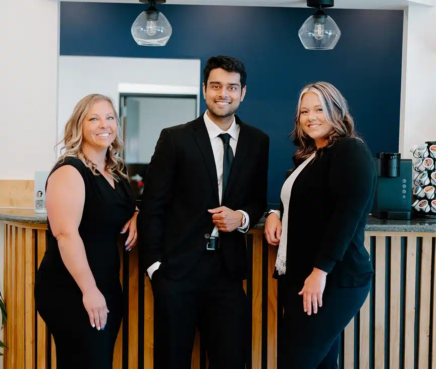 Dr. Dushyant Patel posing with two female medical clinic staff members in an office reception area.